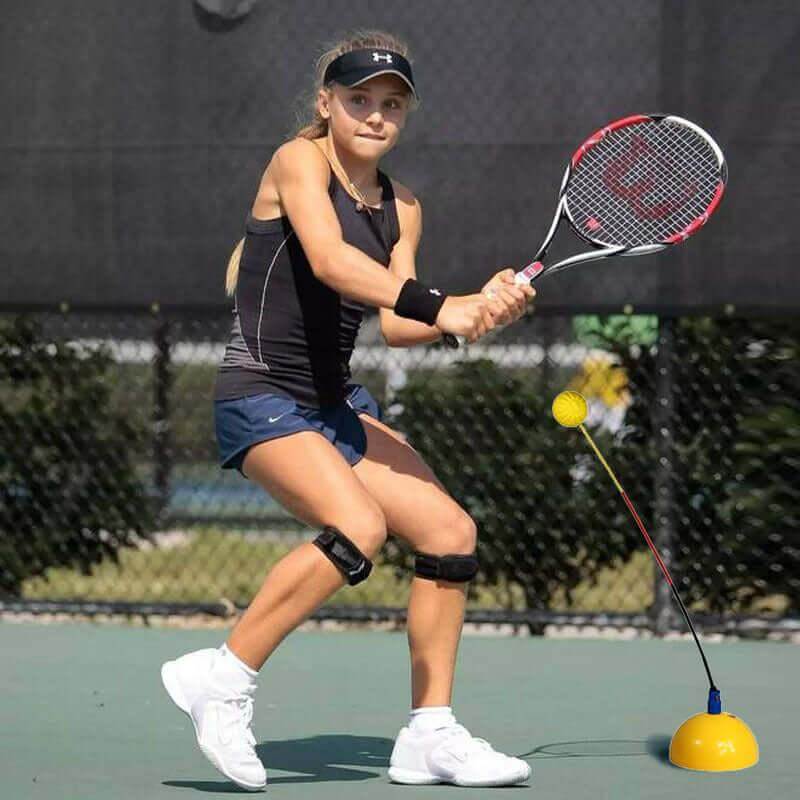 Girl practicing with tennis training equipment for solo practice, using a racket and rebound ball on the court.