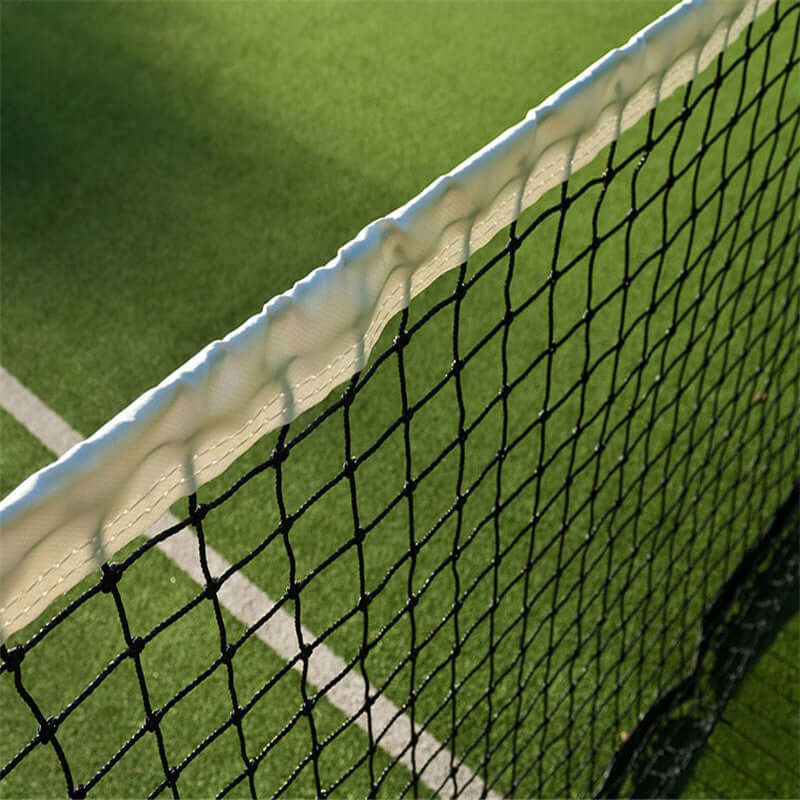 Professional tennis court net in contrast with  green court surface, highlighting its durability and design.