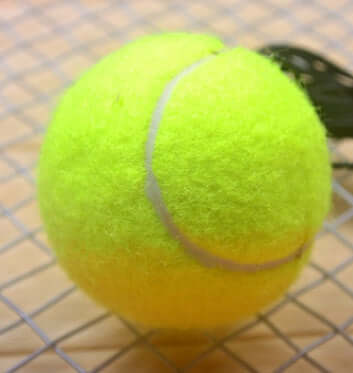 Tennis with Tennis String - bright yellow tennis ball on a grid surface for practice and training sessions.