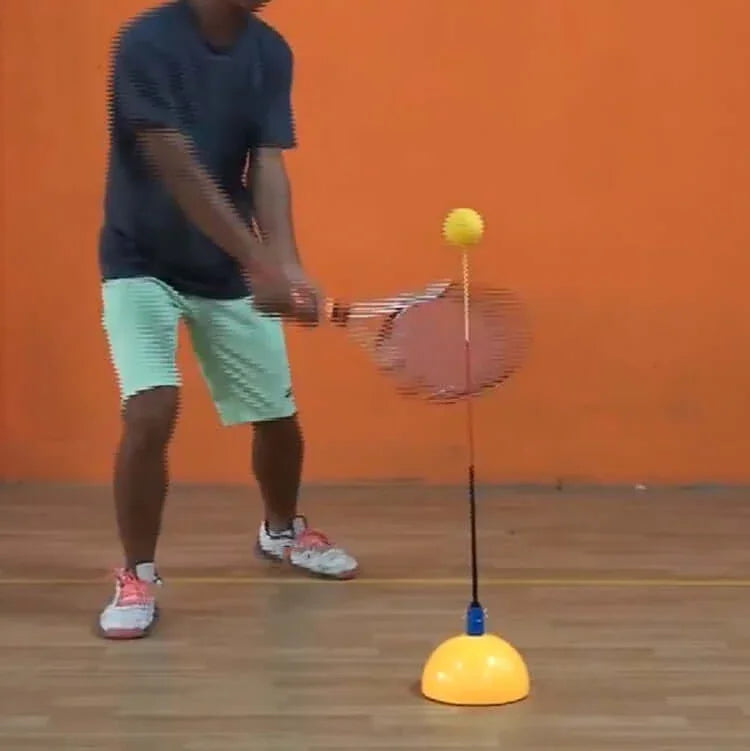Person using a portable tennis trainer during practice in a gym setting.