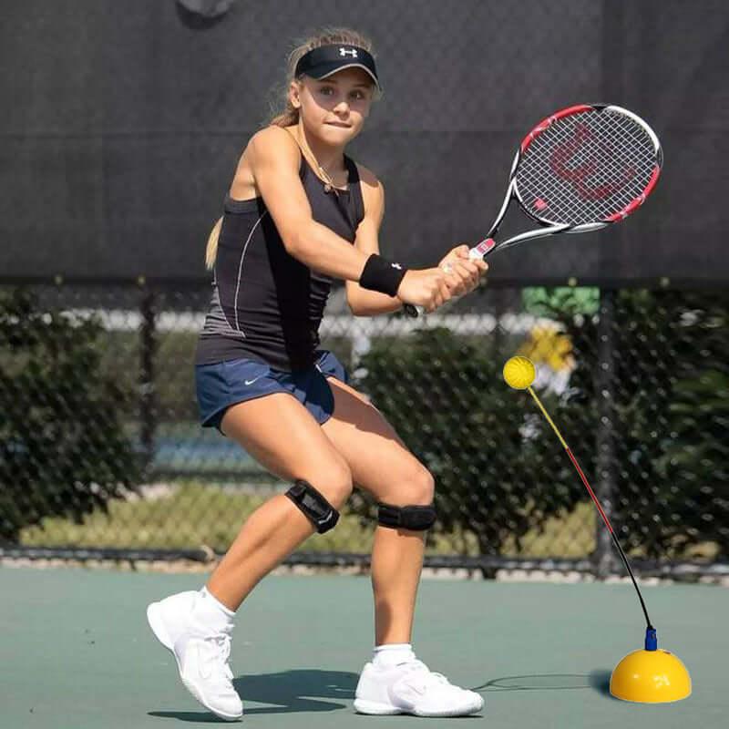Girl practicing tennis with portable tennis trainer on the court under the sun.