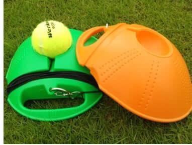 Beginner tennis training equipment including a green base with a yellow tennis ball and an orange training device.